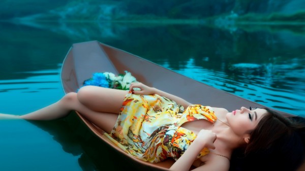 Красивая девушка брюнетка в лодке на озере