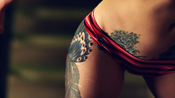 Фото девушки с татуировками на ножке и внизу живота