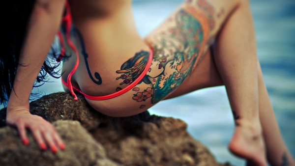 Татуировка на теле девушки на фоне моря